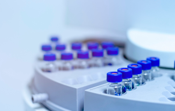 Blue shade picture of close up vials in autosampler of gas chromatography with spectrometer in chemical laboratory