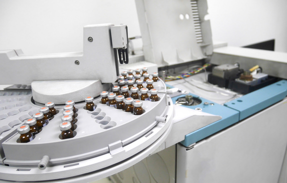 A circular autosampler equipped with dozens of 2 mL glass sample vials